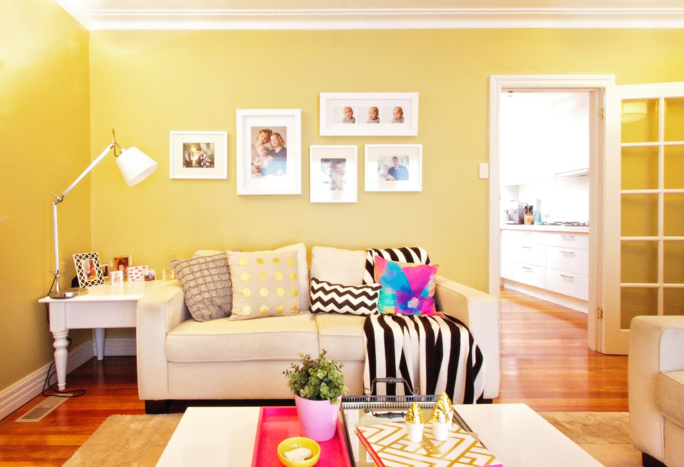 Свежая идея для дизайна: парадная, открытая гостиная комната в современном стиле с желтыми стенами, паркетным полом среднего тона, стандартным камином и фасадом камина из дерева - отличное фото интерьера