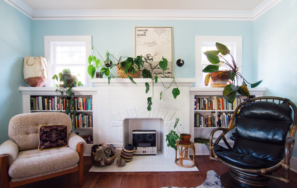 Immagine di un soggiorno eclettico di medie dimensioni con libreria, pareti blu, pavimento in legno massello medio e nessuna TV