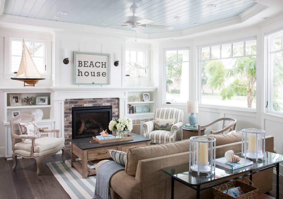 サンディエゴにあるビーチスタイルのおしゃれなリビング (白い壁、濃色無垢フローリング、標準型暖炉、レンガの暖炉まわり、茶色い床、塗装板張りの天井) の写真