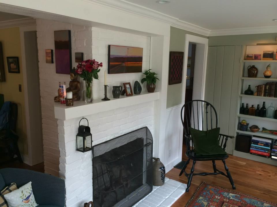 Exempel på ett litet klassiskt separat vardagsrum, med gröna väggar, mellanmörkt trägolv, en standard öppen spis och en spiselkrans i tegelsten