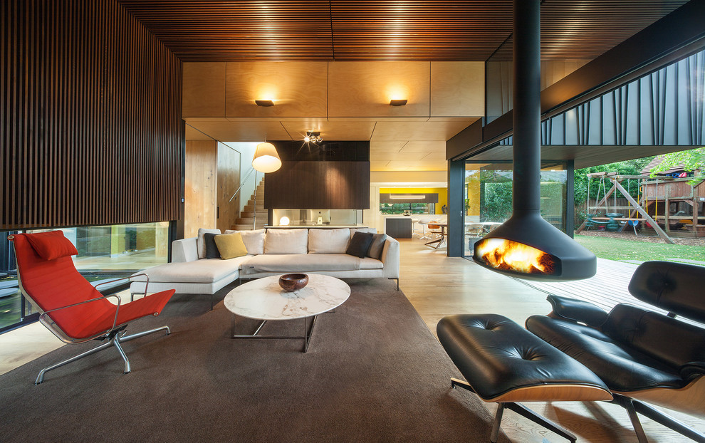 Offenes Modernes Wohnzimmer mit hellem Holzboden und Hängekamin in Melbourne