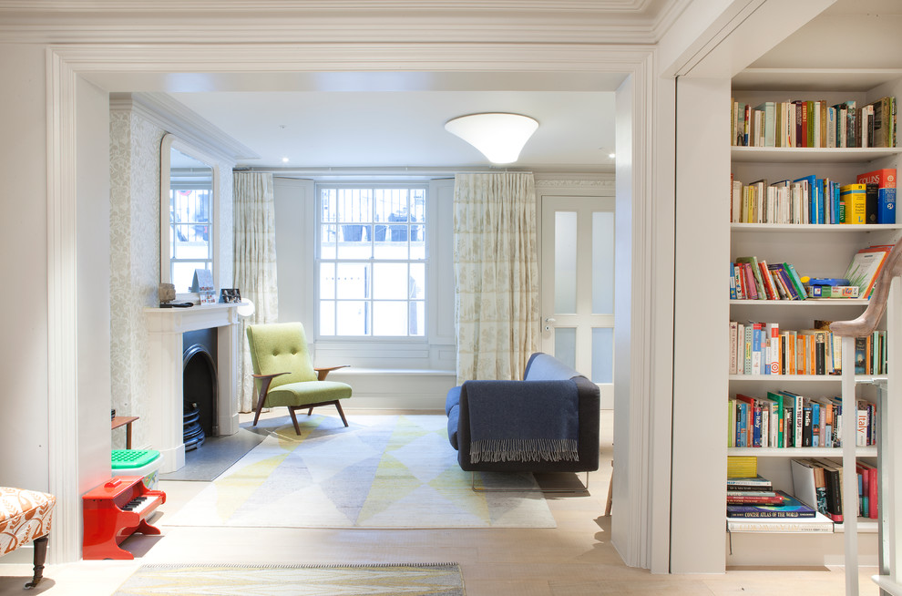 На фото: гостиная комната в скандинавском стиле с белыми стенами, светлым паркетным полом и стандартным камином