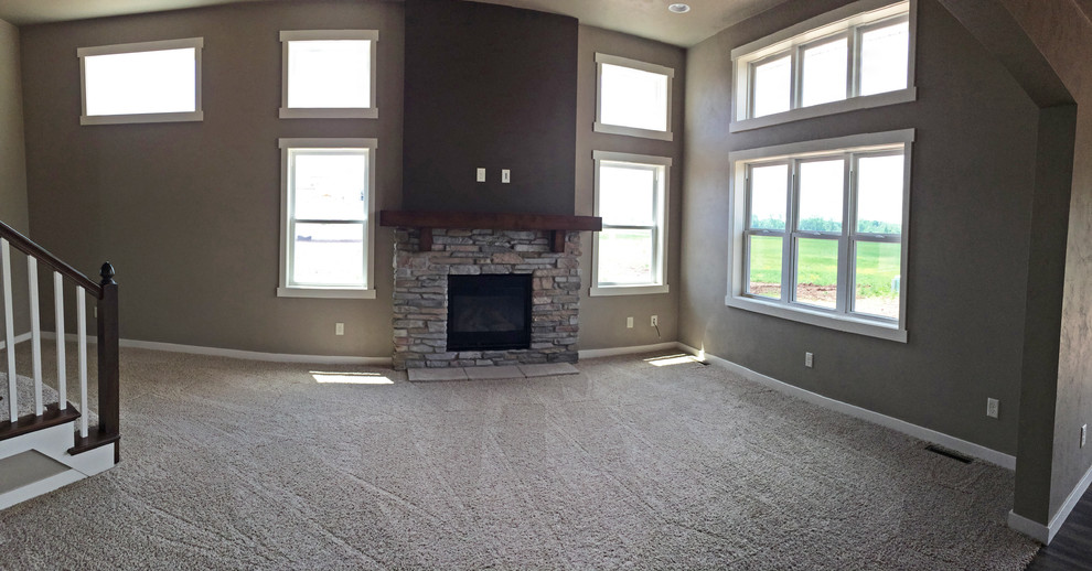 Mittelgroßes, Offenes Rustikales Wohnzimmer mit beiger Wandfarbe, Teppichboden, Kamin, Kaminumrandung aus Stein und TV-Wand in Milwaukee