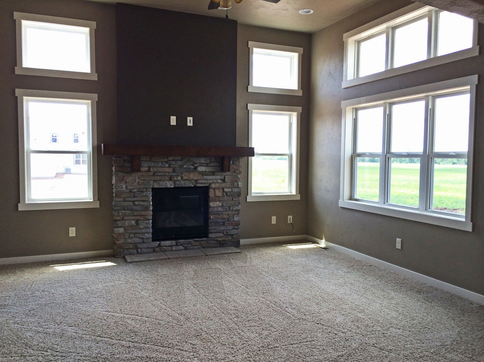 Modelo de salón abierto de estilo americano de tamaño medio con paredes beige, moqueta, todas las chimeneas, marco de chimenea de piedra y televisor colgado en la pared