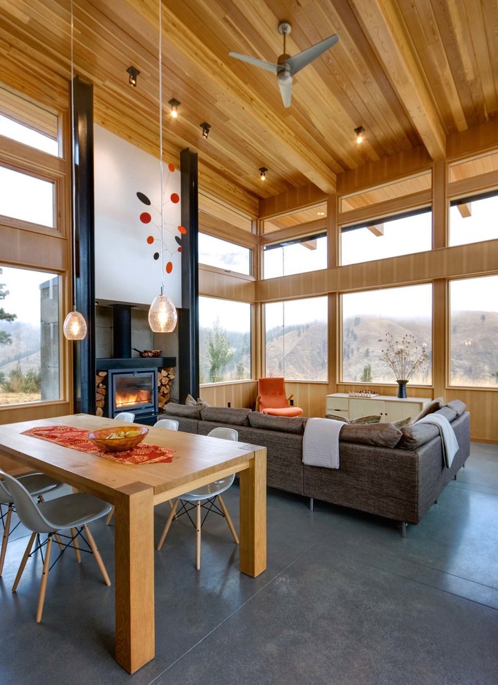 Contemporary open plan living room in Seattle with white walls, concrete flooring, a wood burning stove, a concrete fireplace surround and grey floors.