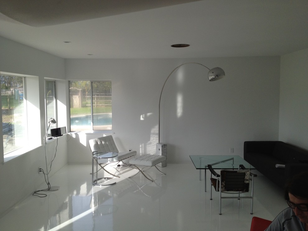 Aménagement d'un salon moderne ouvert avec un mur blanc et un sol blanc.