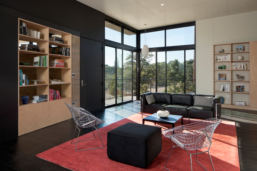 Foto de biblioteca en casa abierta contemporánea de tamaño medio sin chimenea y televisor con paredes negras y suelo de madera pintada