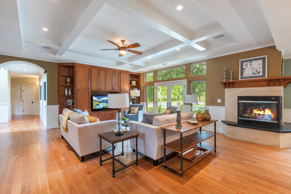 Medium sized traditional formal open plan living room in Sacramento with brown walls, medium hardwood flooring, a corner fireplace, a tiled fireplace surround, a freestanding tv and brown floors.