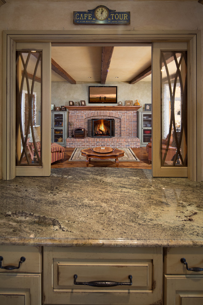 Cette photo montre un grand salon chic avec un sol en bois brun, une cheminée standard et un manteau de cheminée en brique.