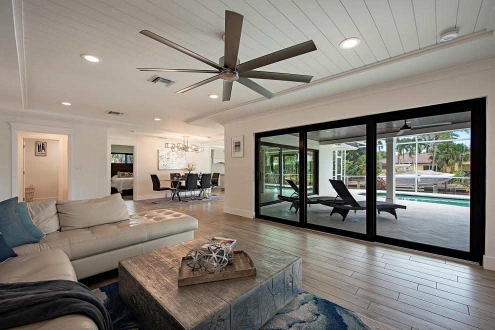 Foto di un piccolo soggiorno costiero aperto con sala formale, pareti bianche, pavimento con piastrelle in ceramica, TV autoportante e pavimento marrone