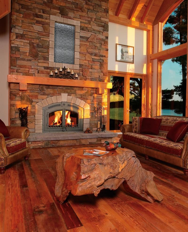 グランドラピッズにある広いラスティックスタイルのおしゃれなリビング (白い壁、無垢フローリング、標準型暖炉、石材の暖炉まわり、テレビなし、茶色い床) の写真