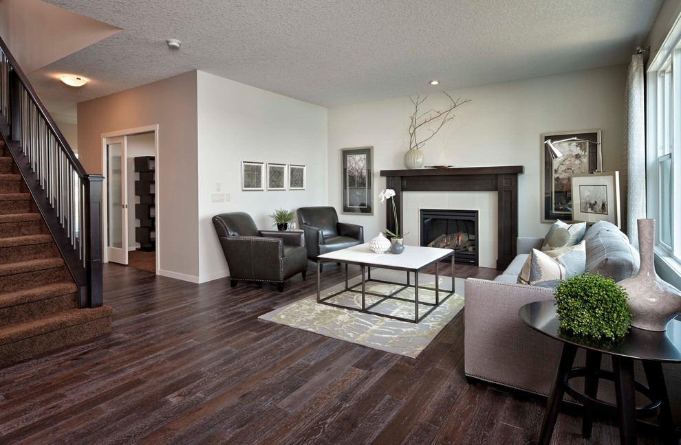 Modernes Wohnzimmer mit beiger Wandfarbe, dunklem Holzboden und Kamin in Calgary