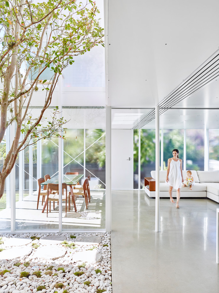 Стильный дизайн: открытая гостиная комната среднего размера в современном стиле с белыми стенами и бетонным полом - последний тренд