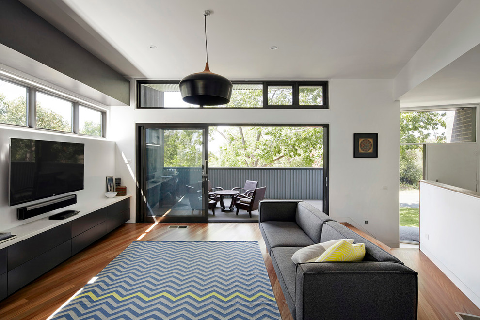Mittelgroßes Modernes Wohnzimmer ohne Kamin mit weißer Wandfarbe, TV-Wand und braunem Holzboden in Melbourne