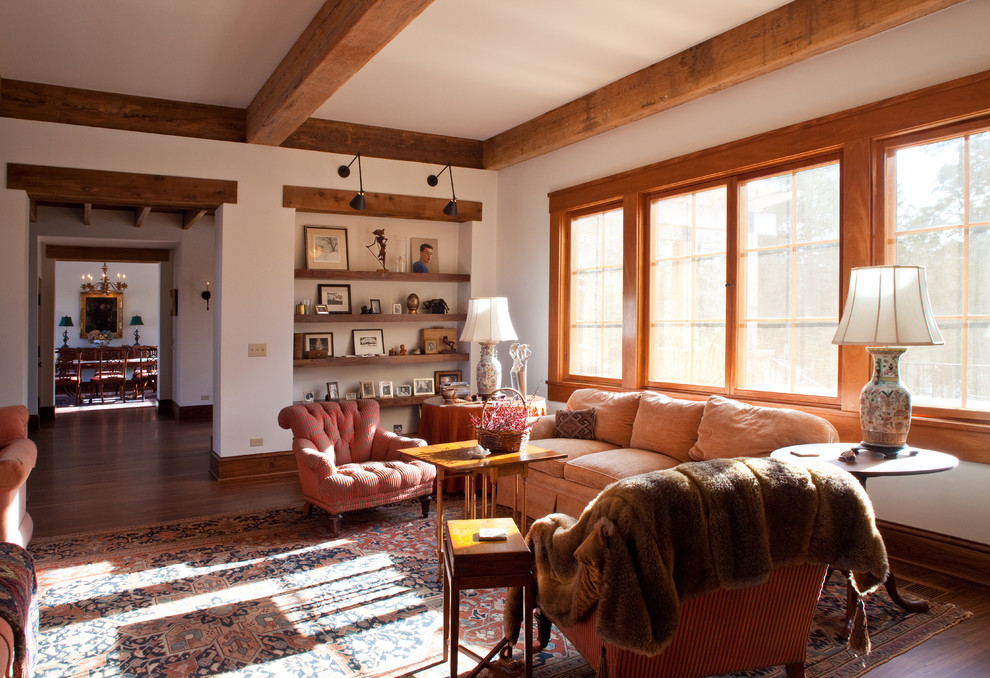 Cette photo montre un salon montagne fermé avec un sol en bois brun, un mur beige, une cheminée standard, aucun téléviseur et un manteau de cheminée en pierre.