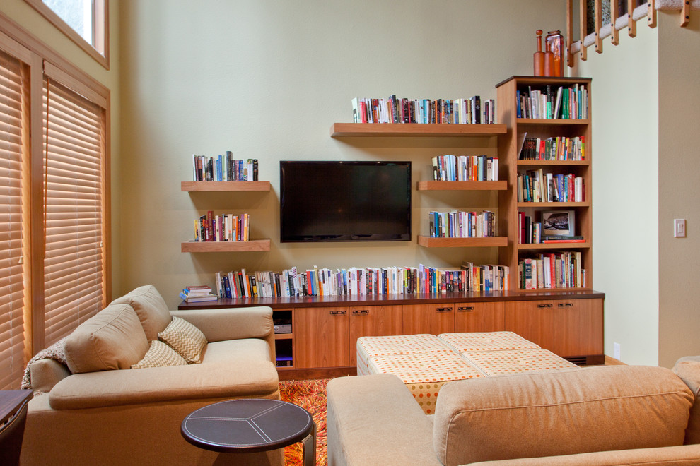 На фото: открытая гостиная комната среднего размера в современном стиле с с книжными шкафами и полками, зелеными стенами, полом из бамбука и телевизором на стене без камина