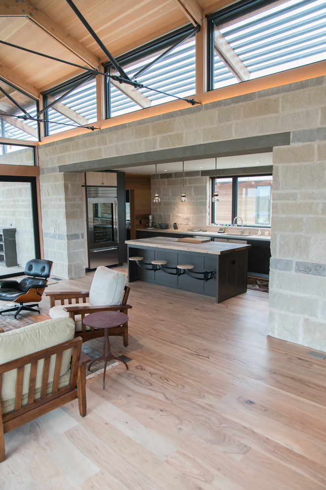 Industrial open plan living room in Austin with light hardwood flooring.