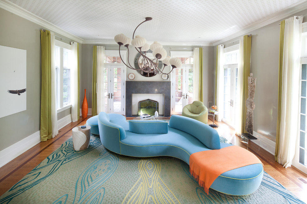 На фото: гостиная комната в стиле фьюжн с зелеными стенами, паркетным полом среднего тона, стандартным камином и синим диваном с