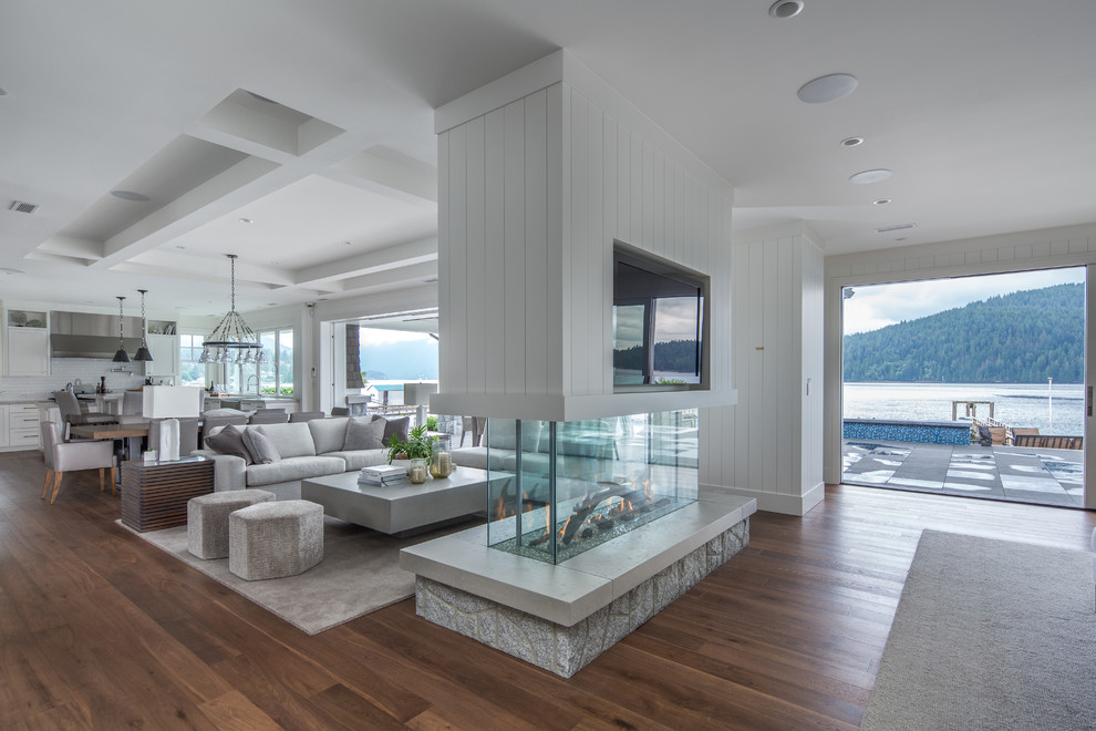 Стильный дизайн: открытая гостиная комната в морском стиле с белыми стенами, темным паркетным полом, двусторонним камином и коричневым полом - последний тренд