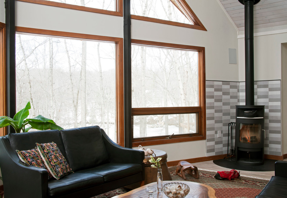 Inredning av ett minimalistiskt mellanstort loftrum, med vita väggar, ljust trägolv, en öppen vedspis och en spiselkrans i trä