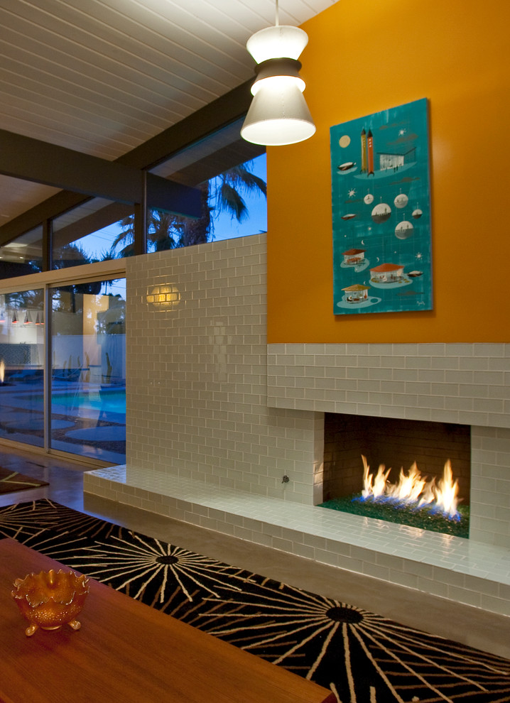 Foto di un ampio soggiorno moderno aperto con pareti bianche, pavimento in cemento, camino classico, cornice del camino piastrellata e TV a parete