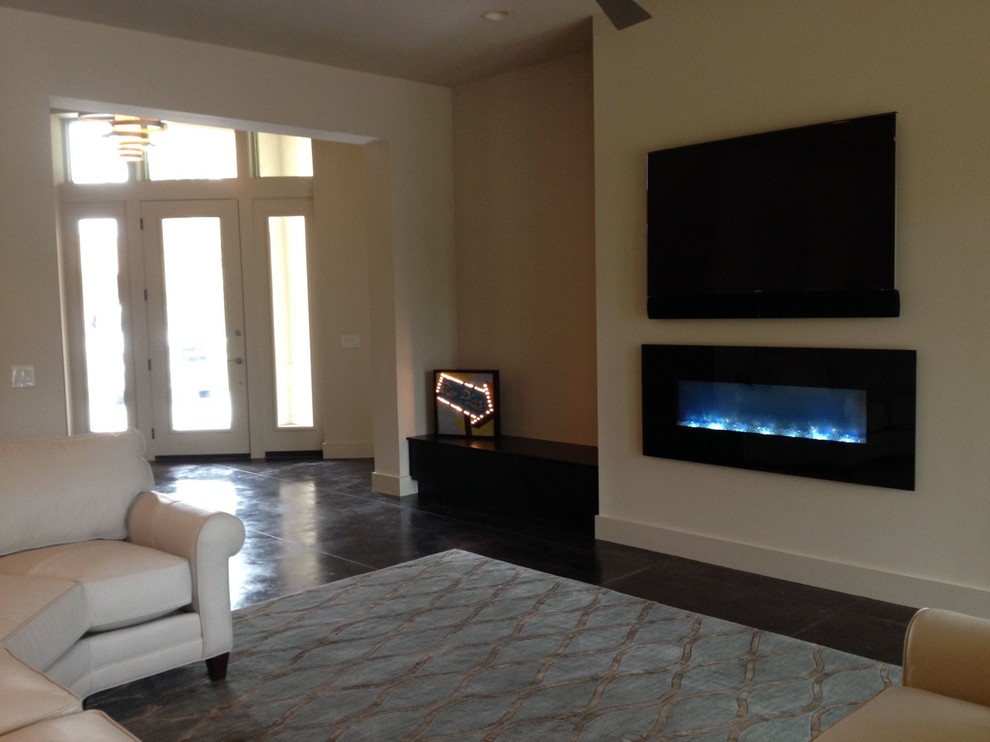 Esempio di un soggiorno design con pareti beige, pavimento in cemento, camino classico e TV a parete