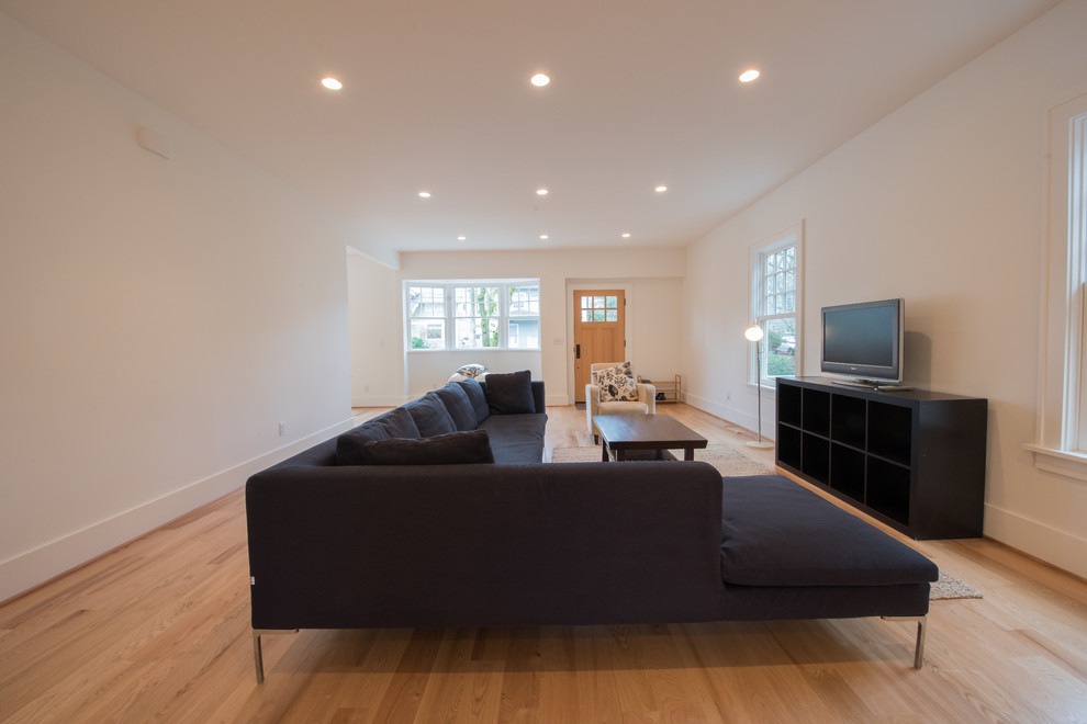This is an example of a large modern open plan living room in Omaha with white walls, light hardwood flooring, no fireplace, a freestanding tv and beige floors.