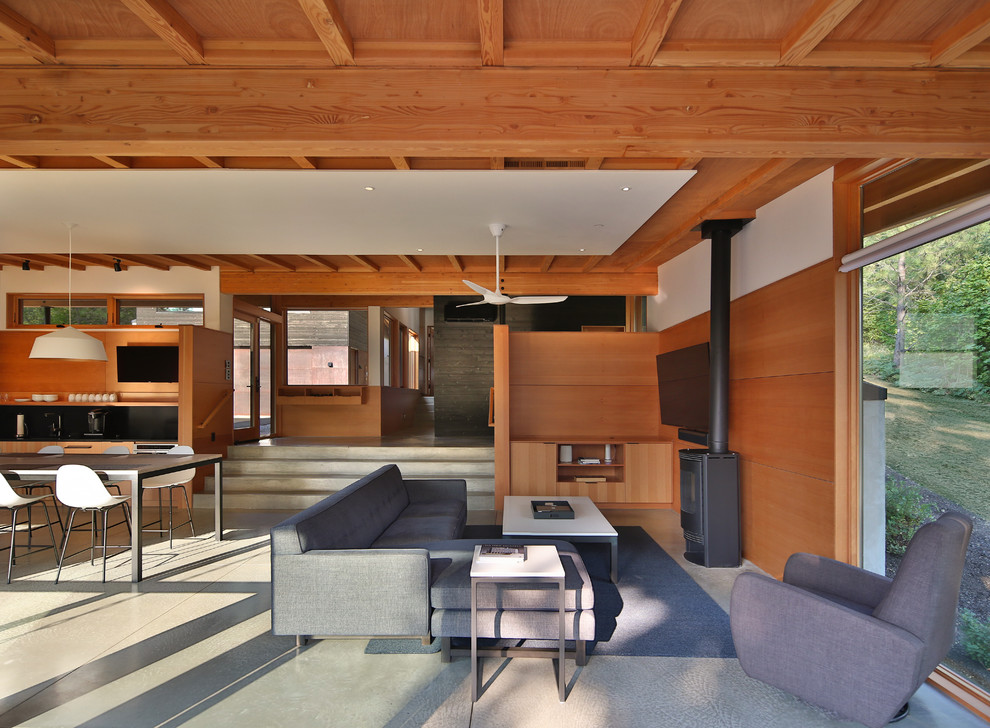 Cette photo montre un salon moderne de taille moyenne et ouvert avec un mur multicolore, sol en béton ciré, un poêle à bois et un sol gris.