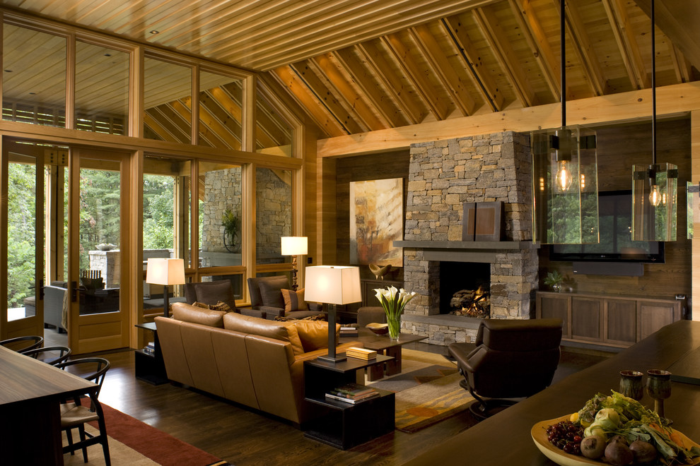 Rustic open plan living room in Charlotte with dark hardwood flooring, a standard fireplace, a stone fireplace surround, brown floors and feature lighting.