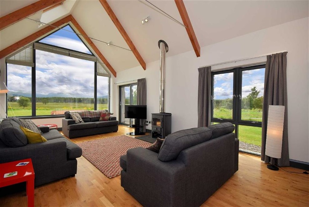 Immagine di un soggiorno minimal di medie dimensioni con pareti bianche, parquet chiaro, stufa a legna e pavimento marrone