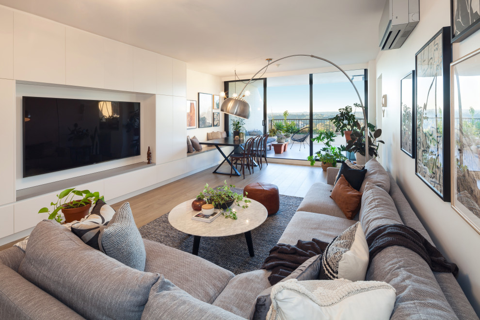 Modernes Wohnzimmer mit weißer Wandfarbe, braunem Holzboden, TV-Wand und braunem Boden in Sydney