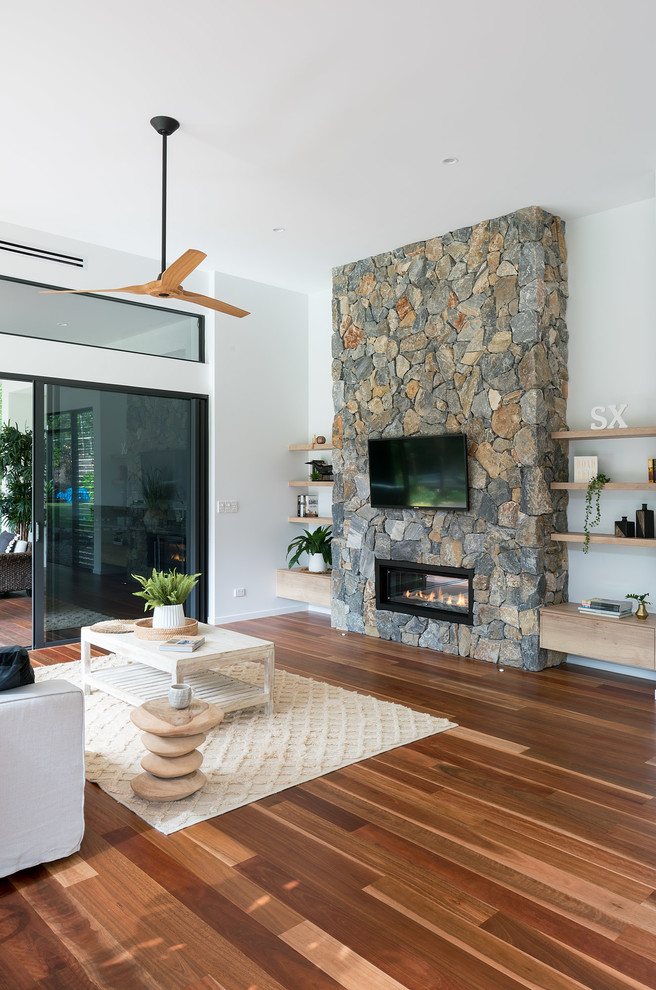 This is an example of a medium sized contemporary open plan living room in Sunshine Coast with multi-coloured walls, medium hardwood flooring, a standard fireplace, a stone fireplace surround, a wall mounted tv and multi-coloured floors.