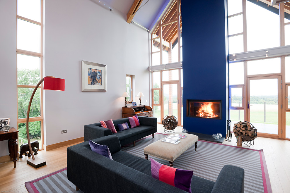 Cette photo montre un salon tendance ouvert avec une salle de réception, un mur multicolore, un sol en bois brun, une cheminée ribbon et canapé noir.