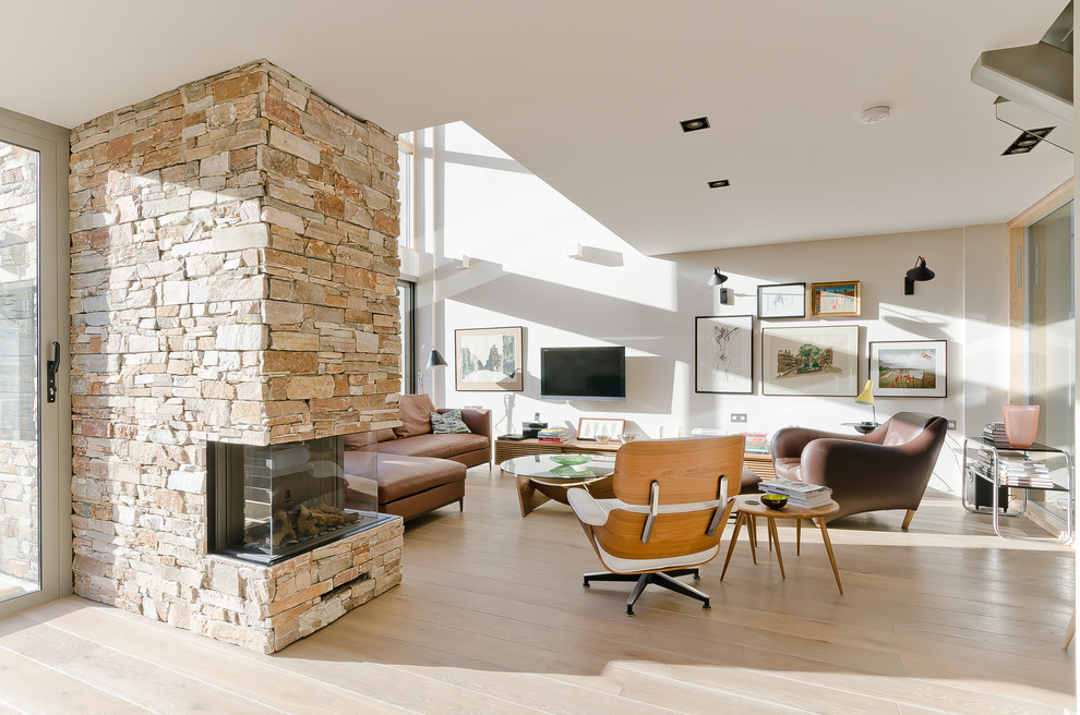 Offenes Nordisches Wohnzimmer mit weißer Wandfarbe, hellem Holzboden, Kaminumrandung aus Stein und TV-Wand in Surrey
