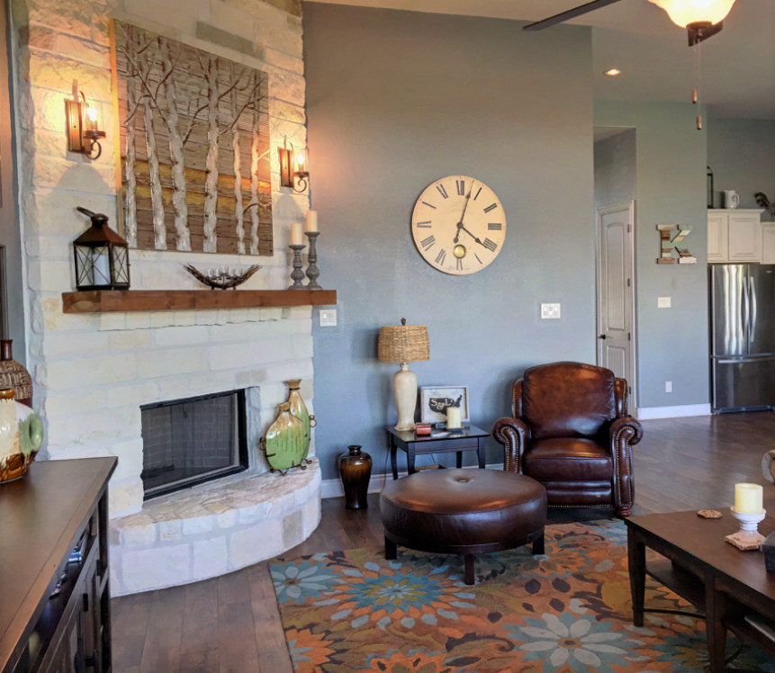 Großes, Offenes Klassisches Wohnzimmer mit grauer Wandfarbe, braunem Holzboden, Eckkamin, Kaminumrandung aus Stein und TV-Wand in Houston