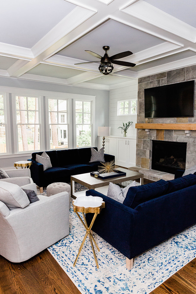 Klassisches Wohnzimmer mit blauer Wandfarbe, braunem Holzboden, Kamin, Kaminumrandung aus Stein, TV-Wand und braunem Boden in Atlanta