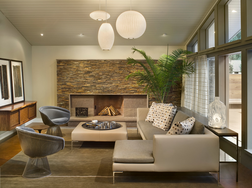 На фото: гостиная комната в современном стиле с фасадом камина из камня с