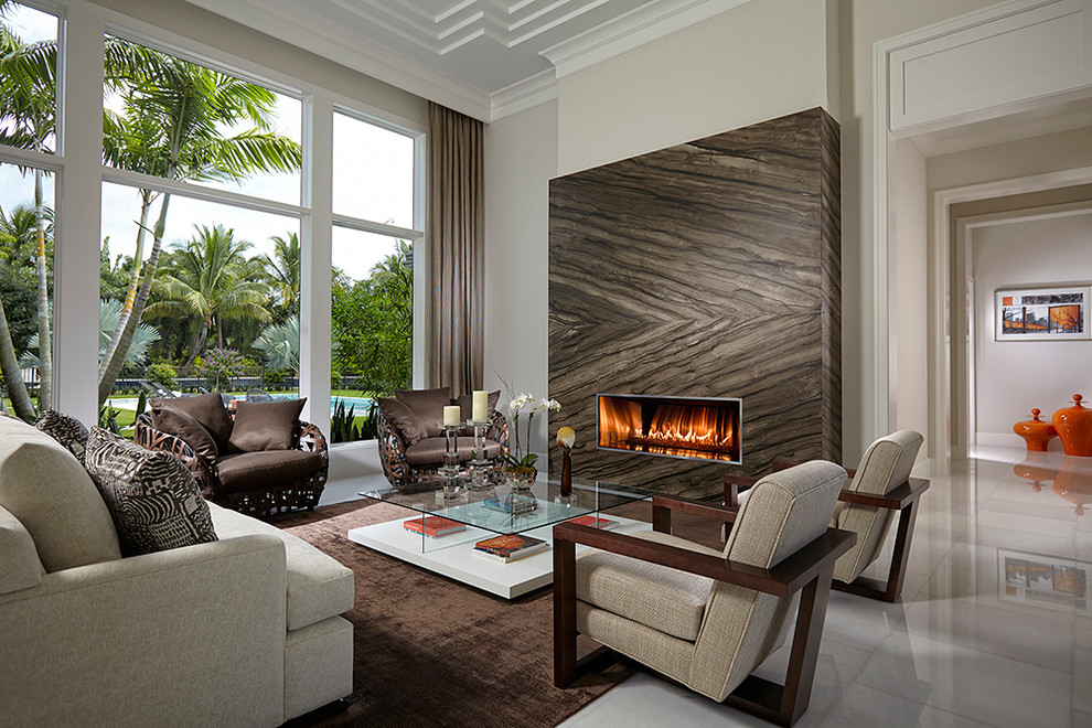マイアミにあるラグジュアリーな広いコンテンポラリースタイルのおしゃれな独立型リビング (ベージュの壁、セラミックタイルの床、標準型暖炉、石材の暖炉まわり、埋込式メディアウォール) の写真