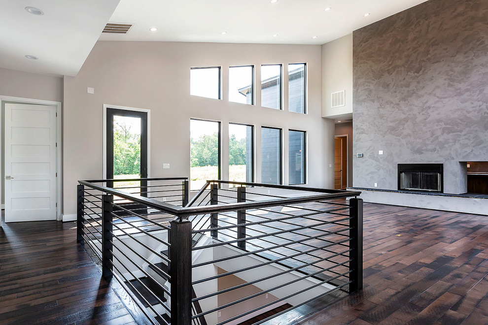 Diseño de salón abierto y abovedado vintage grande con paredes grises, suelo de madera oscura, chimenea de doble cara y marco de chimenea de hormigón