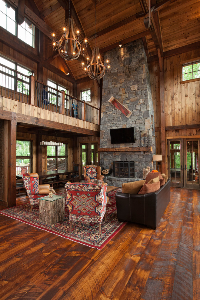 Photo of a large rustic mezzanine living room in Burlington with brown walls, a standard fireplace, a stone fireplace surround, a wall mounted tv, medium hardwood flooring and feature lighting.