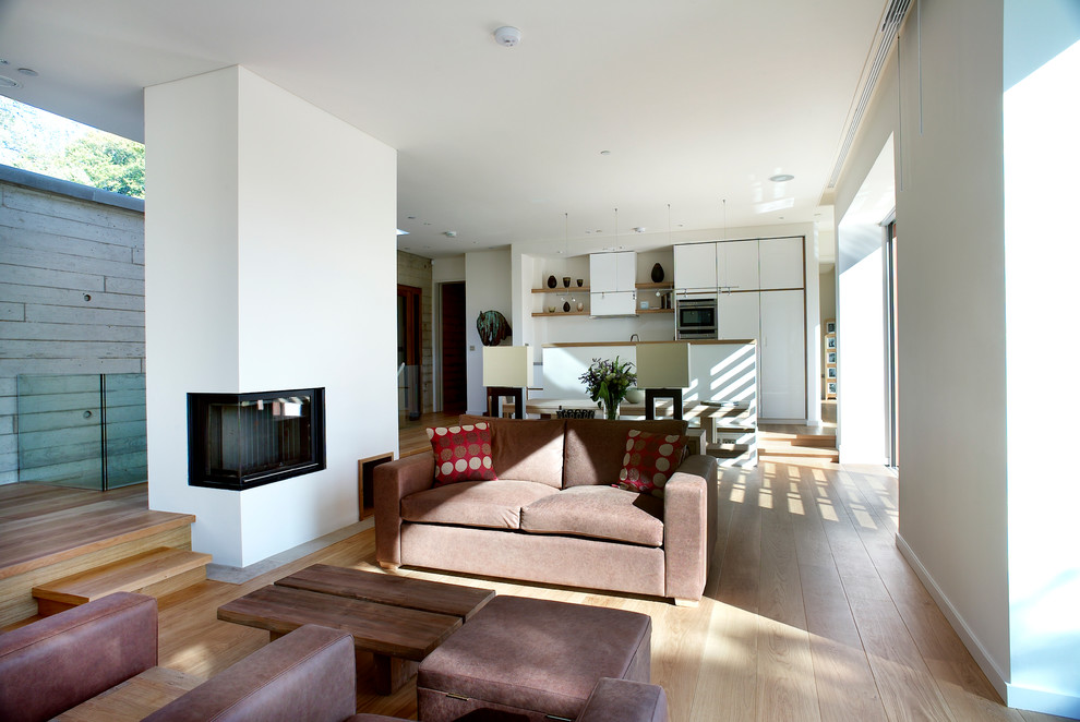 Diseño de salón para visitas abierto moderno de tamaño medio sin televisor con paredes blancas, suelo de madera en tonos medios, marco de chimenea de yeso y chimenea lineal