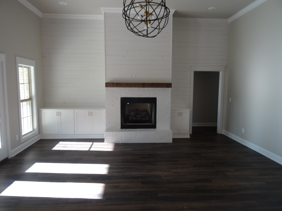 Design ideas for a large farmhouse open plan living room in Other with white walls, dark hardwood flooring, a standard fireplace, a brick fireplace surround, brown floors, a vaulted ceiling and feature lighting.