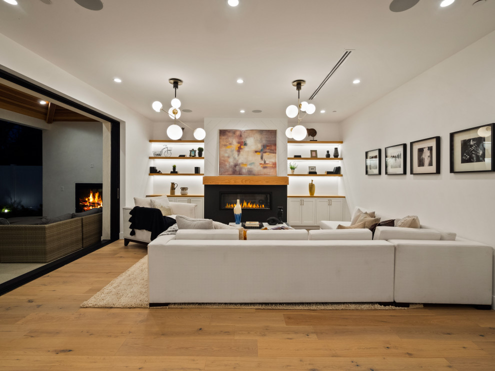 Example of a large cottage formal and open concept light wood floor living room design in Los Angeles with white walls, a standard fireplace, a plaster fireplace and no tv