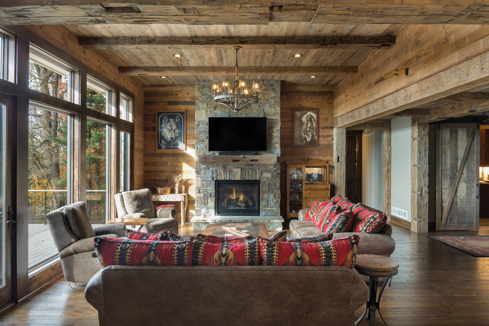 Rustic open plan living room in Minneapolis with a standard fireplace, a stone fireplace surround, a wall mounted tv, brown walls, dark hardwood flooring and brown floors.