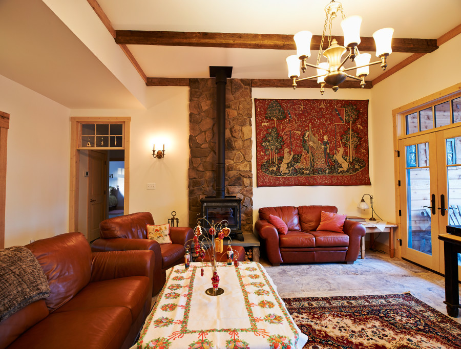Стильный дизайн: изолированная гостиная комната в стиле рустика с белыми стенами, полом из травертина, печью-буржуйкой и фасадом камина из камня - последний тренд