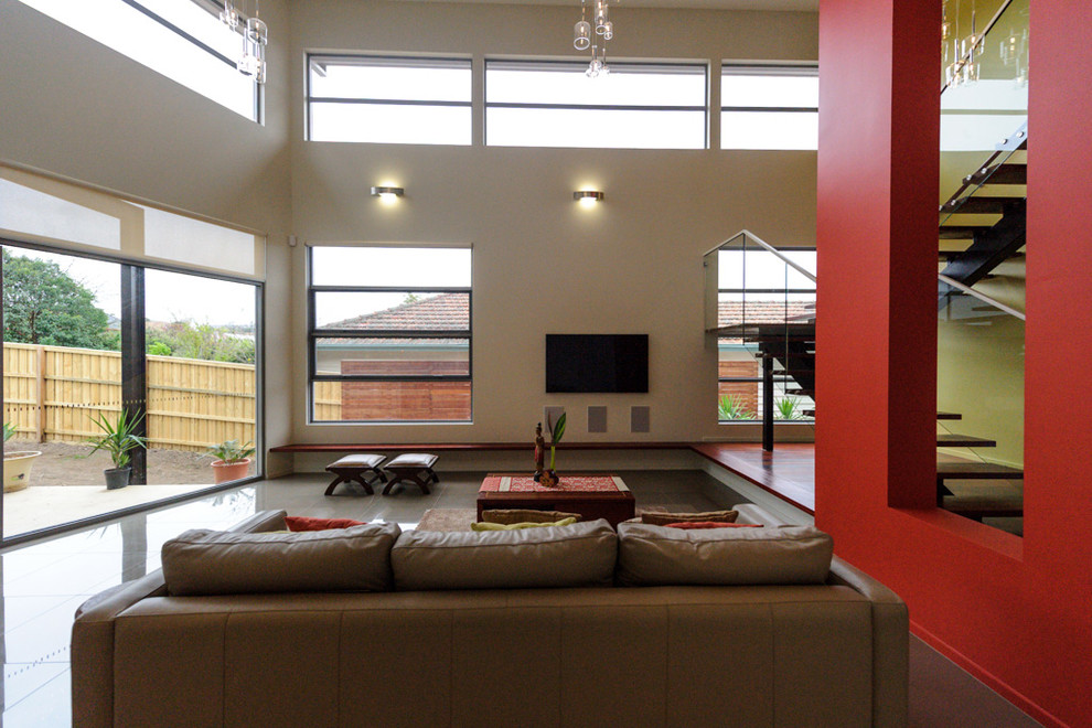 Источник вдохновения для домашнего уюта: открытая гостиная комната среднего размера в современном стиле с белыми стенами, полом из керамогранита, телевизором на стене и серым полом