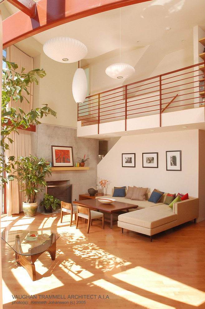 Mittelgroßes, Fernseherloses, Offenes Modernes Wohnzimmer mit grauer Wandfarbe, braunem Holzboden, Kamin und Kaminumrandung aus Beton in Los Angeles