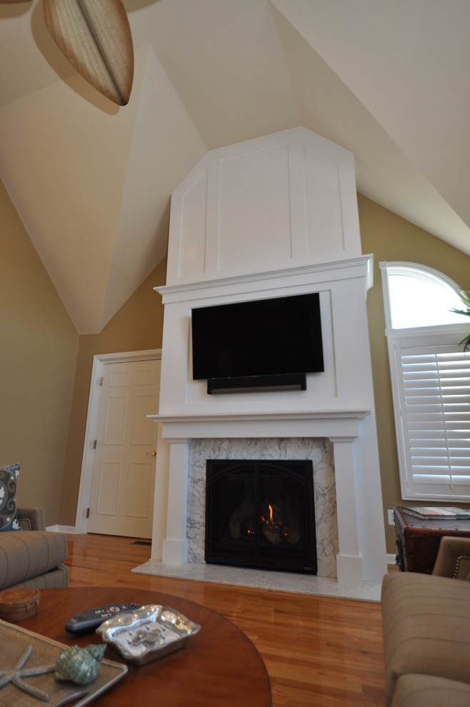 This is an example of a medium sized nautical formal enclosed living room in Philadelphia with beige walls, light hardwood flooring, a standard fireplace, a wall mounted tv and a wooden fireplace surround.