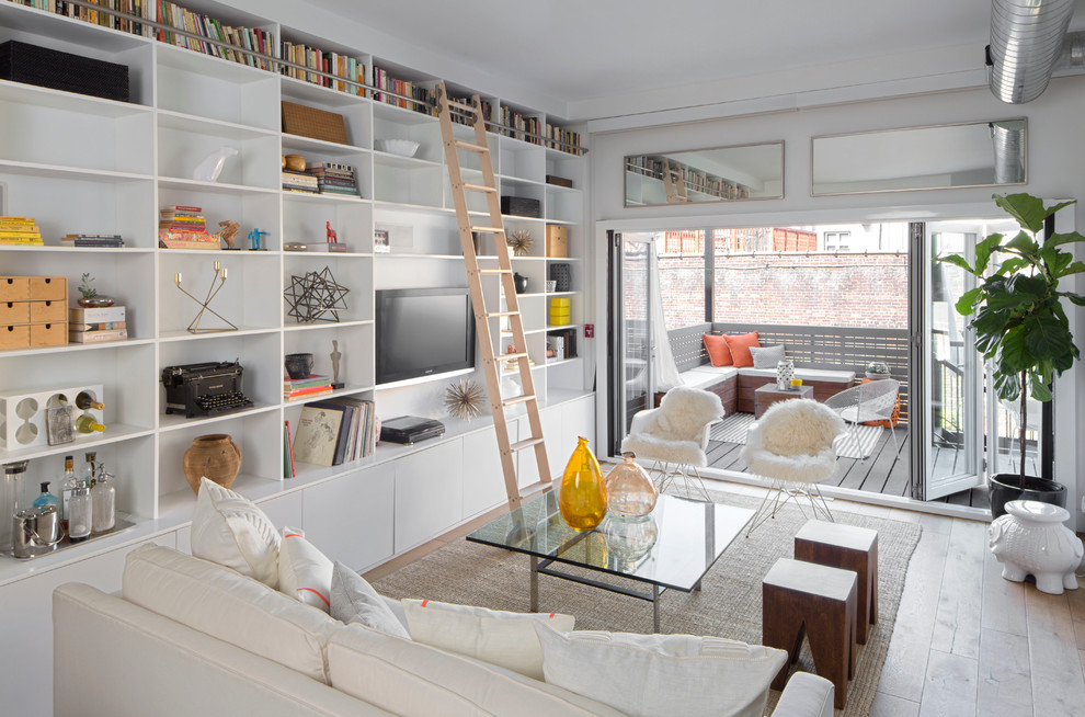 This is an example of a large retro open plan living room in New York with a reading nook, white walls, light hardwood flooring, no fireplace and a built-in media unit.