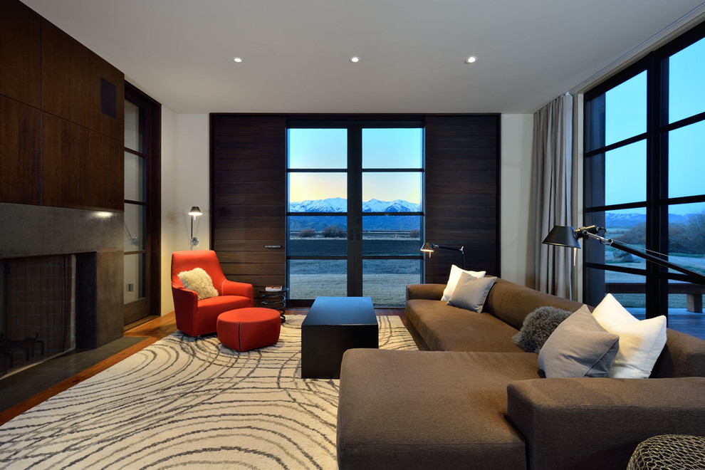 Example of a large trendy enclosed medium tone wood floor living room design in Boise with a standard fireplace, a concrete fireplace, white walls and a concealed tv